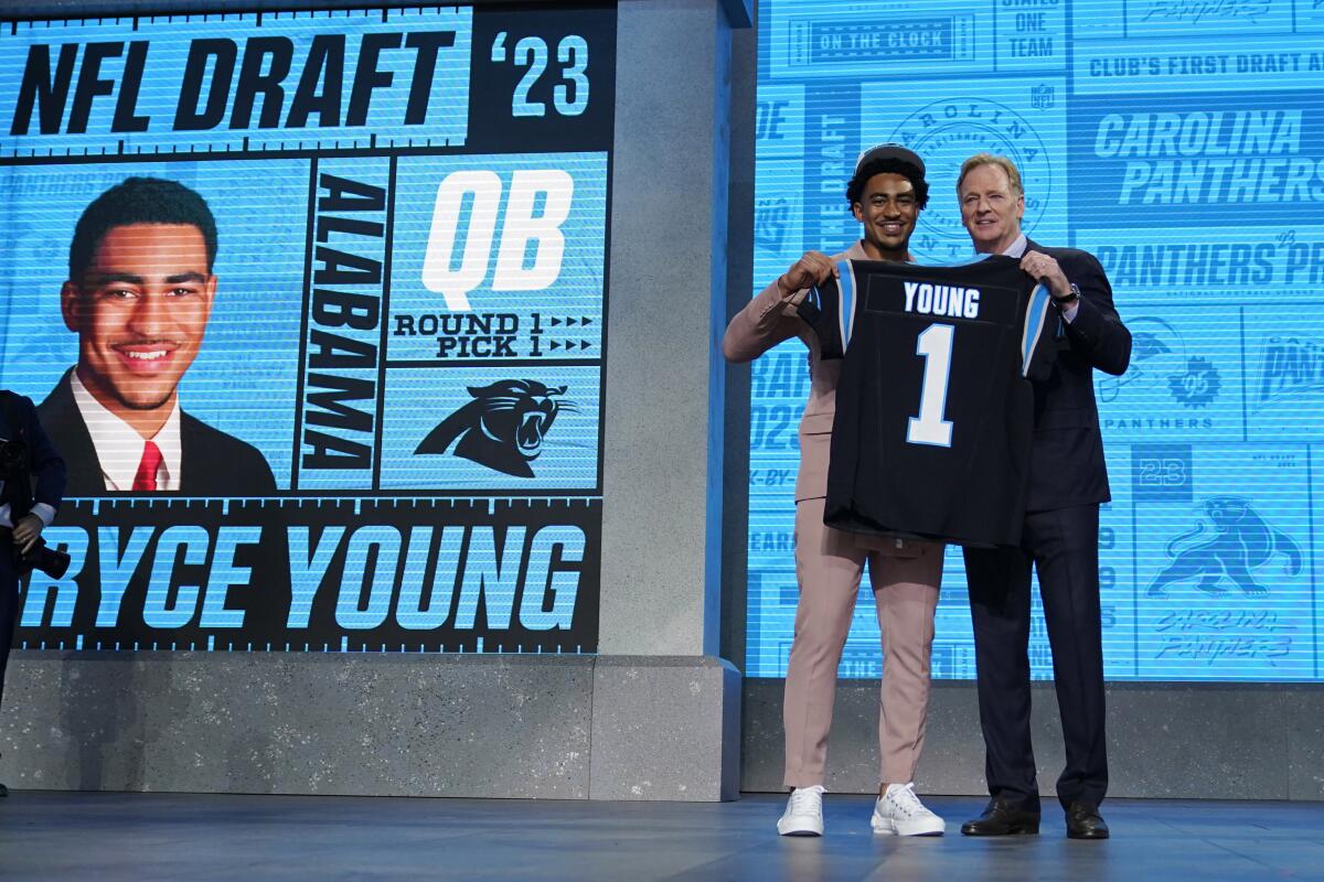 Quarterback Bryce Young holds a Panthers jersey with NFL commissioner Roger Goodell.