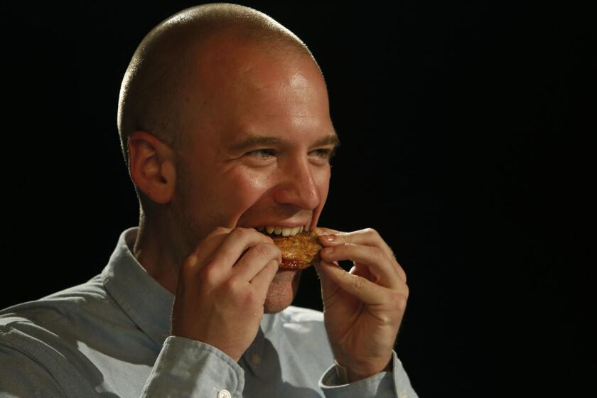 Sean Evans, the host of the YouTube series "Hot Ones," eats a hot wing on the show.