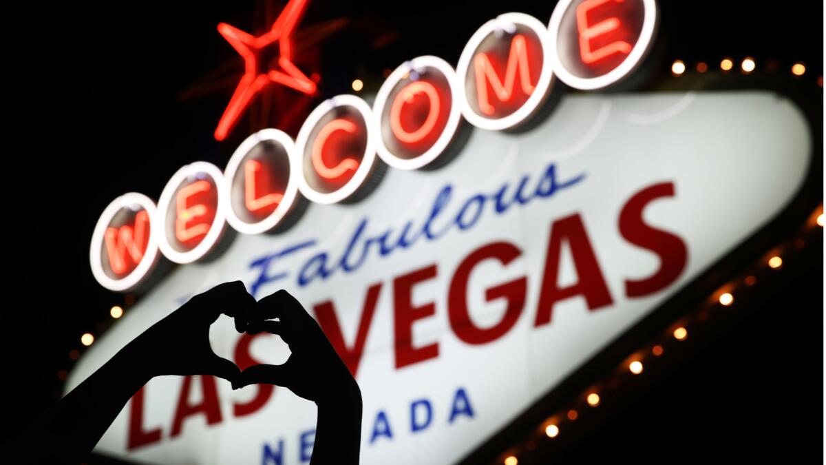 Ragne Domaas of Norway makes a heart symbol with her hands near a makeshift memorial for victims of a mass shooting in Las Vegas.