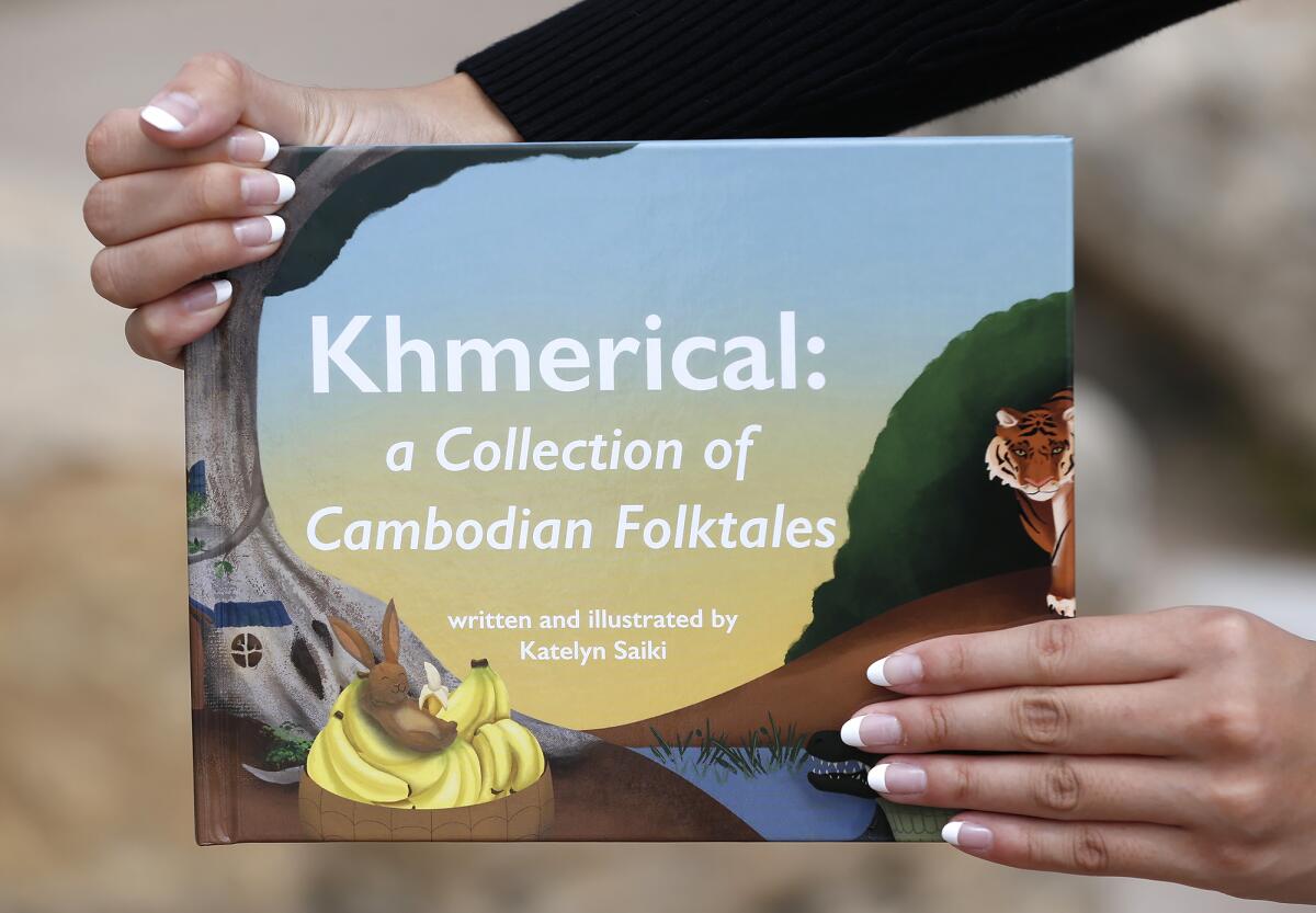 Girl Scout Katelyn Saiki holds her own book "Khmerical: a Collection of Cambodian Folktales."
