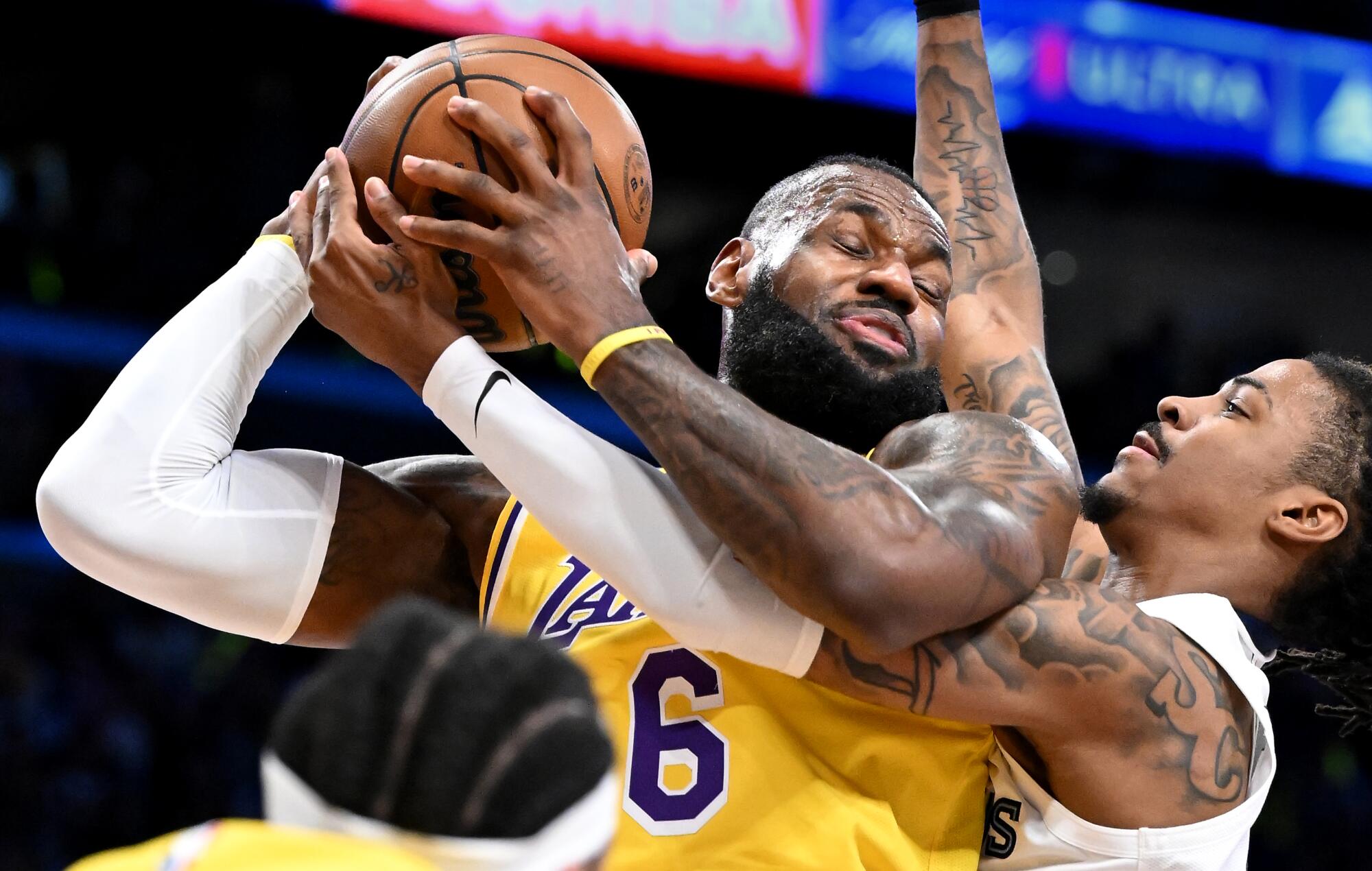 Lakers star LeBron James grabs a rebound away from Memphis Grizzlies star Ja Morant.