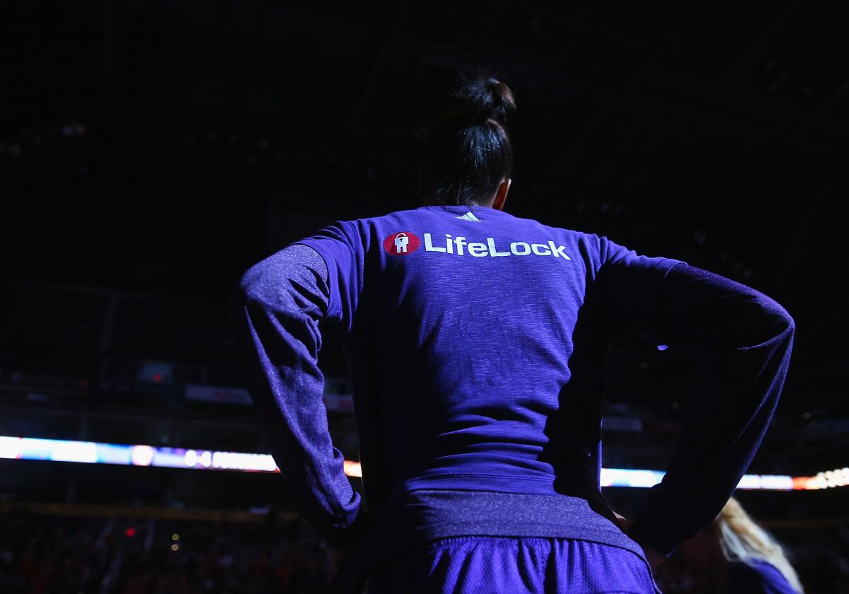 A woman wears a purple shirt with "LifeLock" written on the back.
