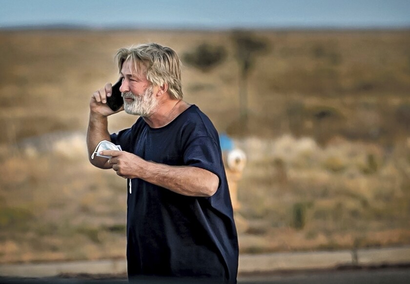 A bearded Alec Baldwin talks on a cellphone outdoors