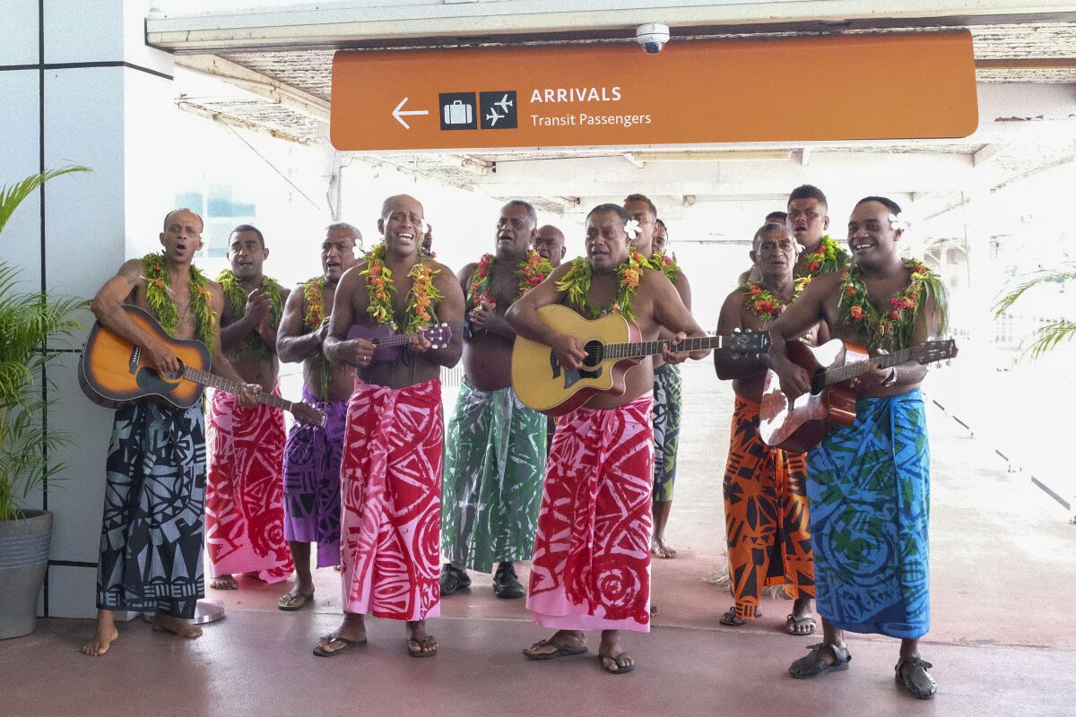 In this photo released by Tourism Fiji, guests receive a traditional Fijian welcome as they arrive at Nadi International airport in Fiji, Wednesday, Dec. 1, 2021. Fiji welcomed back its first tourists in more than 600 days on Wednesday after deciding to push ahead with reopening plans despite the threat posed by the omicron variant. (Bruce Rounds/Tourism Fiji via AP)