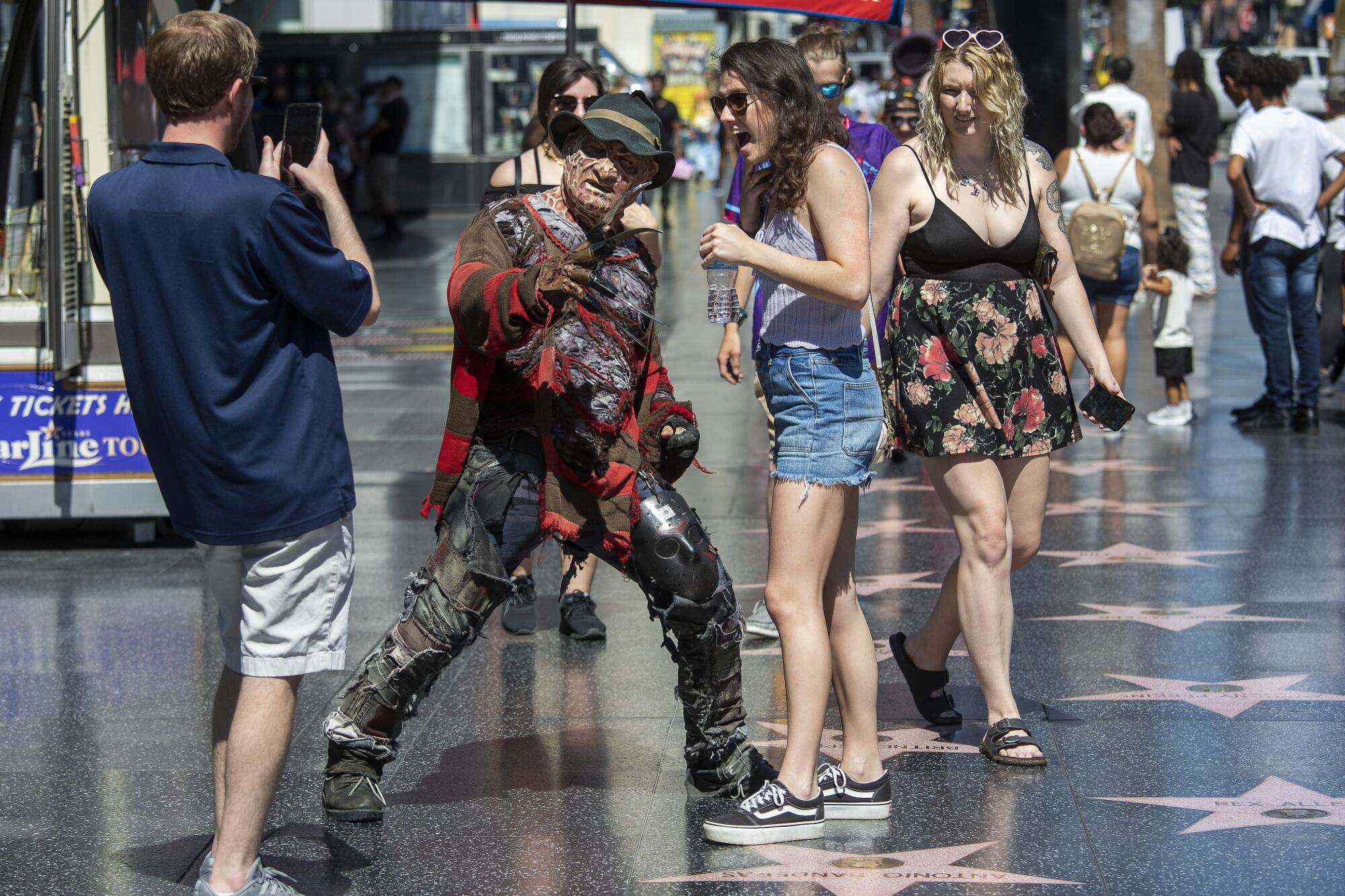 Alex Cannon, left, photographs friend Emilee Williams, posing with a street performer dressed as Freddy Krueger in Hollywood