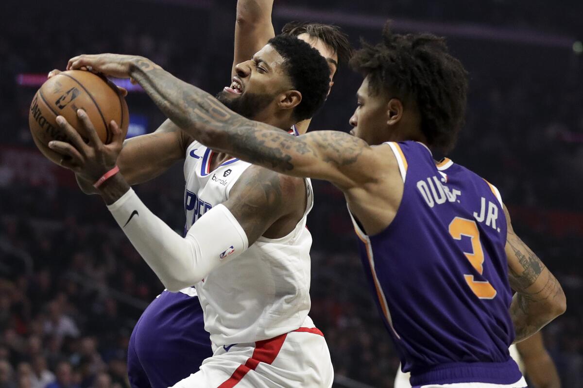 Phoenix Suns forward Kelly Oubre Jr., right, blocks a shot by Clippers forward Paul George.