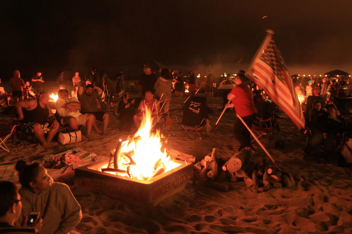 Beachgoers gather around traditional bonfires on July 6, 2013, in Huntington Beach. Beach fires are a long and strongly held tradition in Southern California beach and surfing communities. The Assembly on Monday passed a bill that aims to protect the rings, which have come under fire due to air pollution concerns.