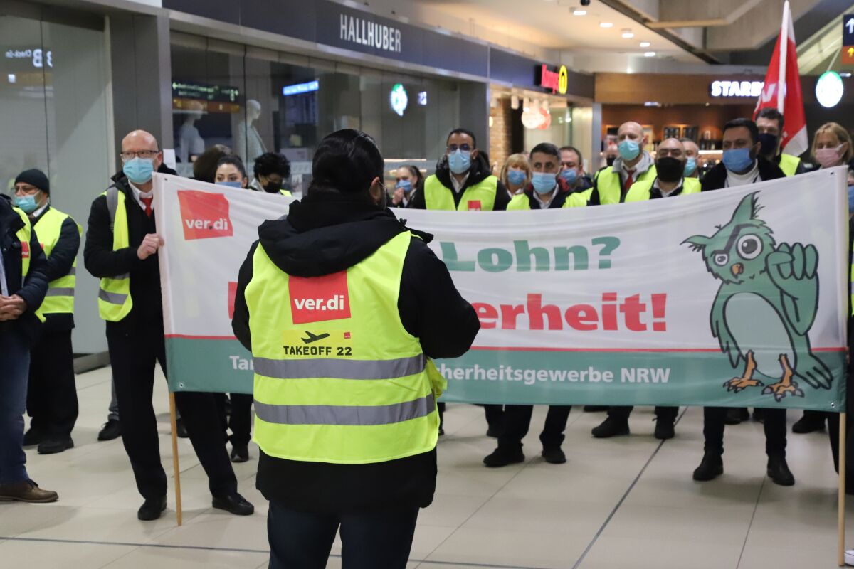 Striking airport staff gather in a terminal in Cologne, Germany, Monday, March 14, 2022. More than 1,000 security personnel have walked off their jobs at airports across Germany, leading to dozens of flight cancellations and delays. Security staffers at airports in Berlin, Dusseldorf, Hannover and elsewhere began their one-day strike early Monday to press for higher wages. (Sascha Thelen/dpa via AP)