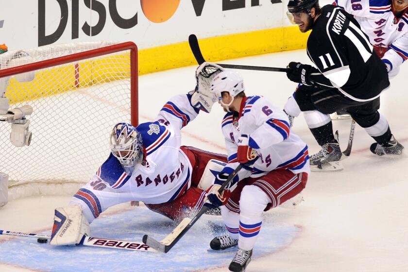 New York Rangers goalie Henrik Lundqvist makes a save on a shot by Kings center Anze Kopitar, top right, as Rangers defenseman Anton Stralman looks on during the third period of the Kings' 3-2 overtime win in Game 1 of the Stanley Cup Final.