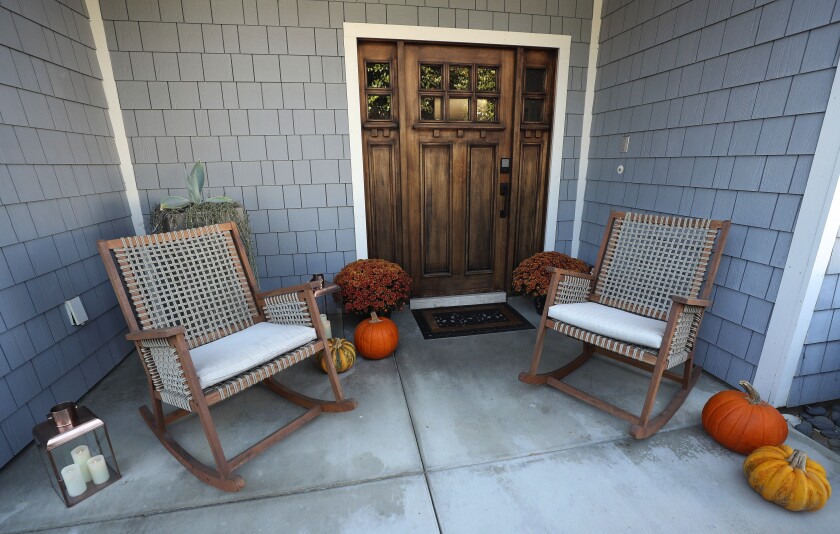 Two chairs sit outside a home entrance decorated for fall