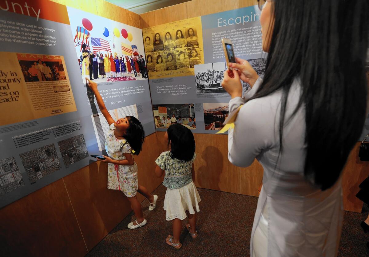 Phuong Tran, 30, photographs her daughters, Tiffany, 5, left, and Angelina, 3, looking at a photo of their grandfather, Gen. Nhut Van Tran and grandmother, Lang Tran. The exhibit, Vietnamese Focus: Generations of Stories, uses photographs, videos, art and other materials to tell the story of O.C.'s Vietnamese community.