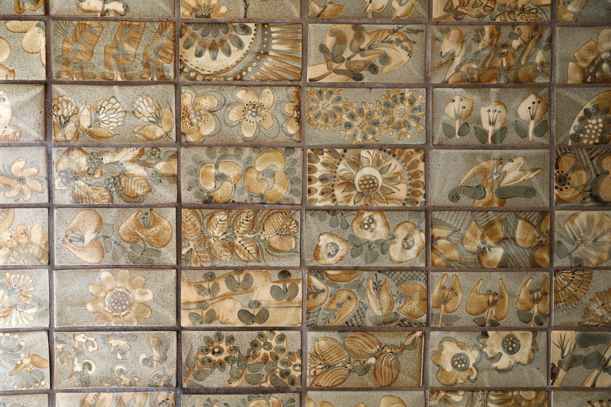 A close-up of hand-painted tiles bearing natural motifs such as flowers and leaves by Dora De Larios