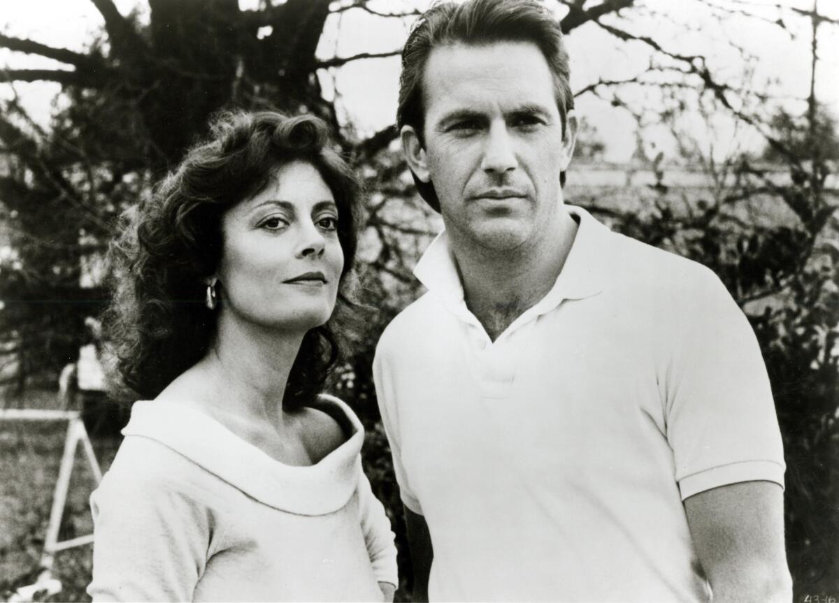 A black-and-white photo of a woman and a man standing outside. 
