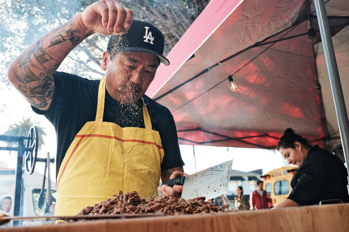 Kogi founder Roy Choi sprinkles seasoning on his al pastor at his new venture, street stand Tacos por Vida in Palms.