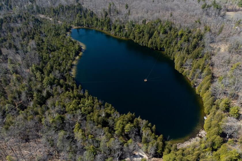 An aerial view of Crawford Lake as a team consisting of scientists from Carleton University and Brock University gather sediment layer samples from the lake bottom at the Crawford Lake Conservation Area near Milton, Ontario, Canada, April 12, 2023. The view under the surface of Crawford Lake tells a different story. Scientists believe the lake's exceptionally well-preserved sediment layers serve as a reference point for a proposed new geological chapter in the planet's history, defined by the considerable changes wrought by human activity: the Anthropocene. The International Commission on Stratigraphy's Anthropocene Working Group on July 11, 2023, named the lake as the embodiment of the proposed Anthropocene epoch. (Photo by Peter POWER / AFP) (Photo by PETER POWER/AFP via Getty Images)