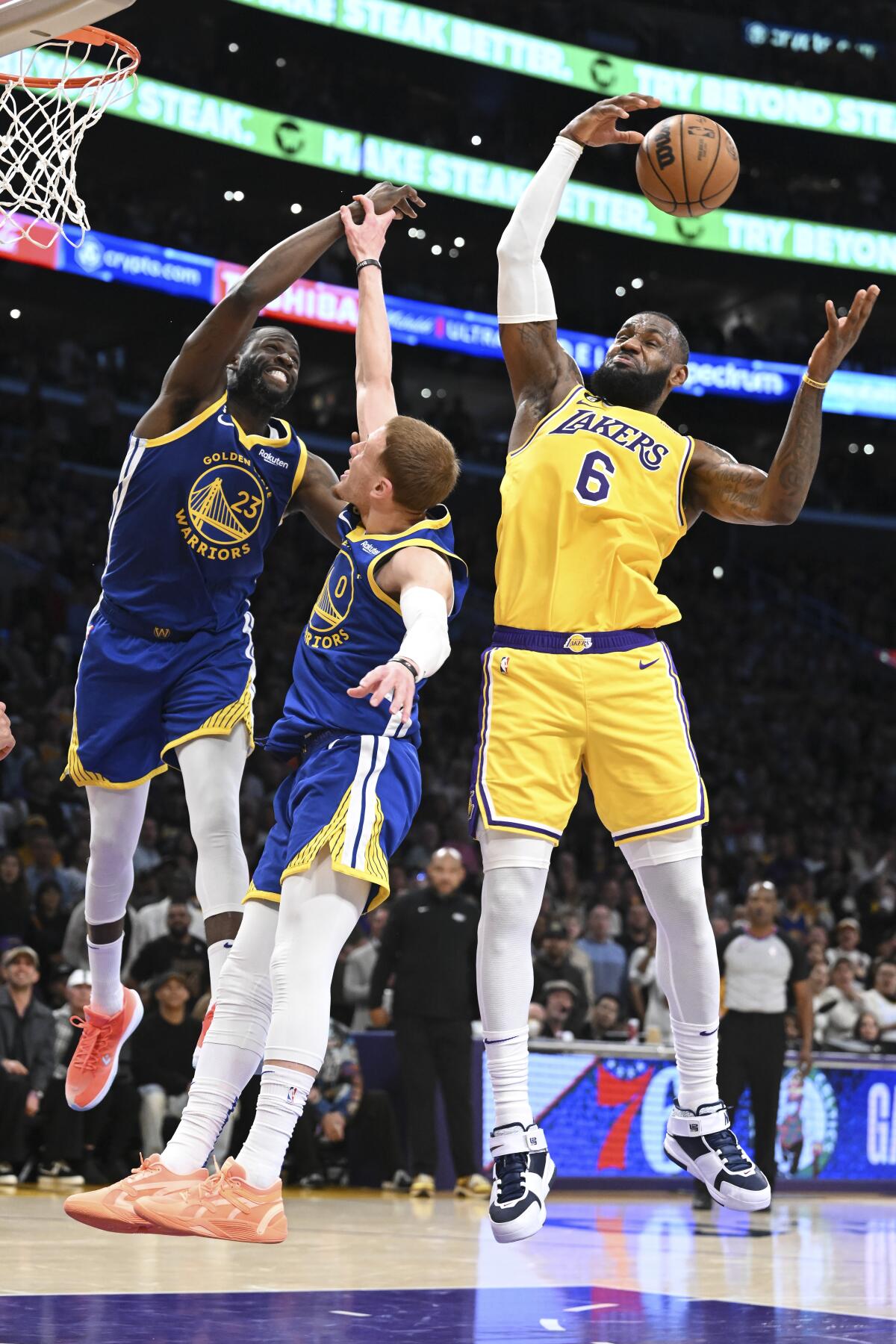 Lakers forward LeBron James, from right, jumps up for a rebound against the Warriors' Donte DiVincenzo and Draymond Green.