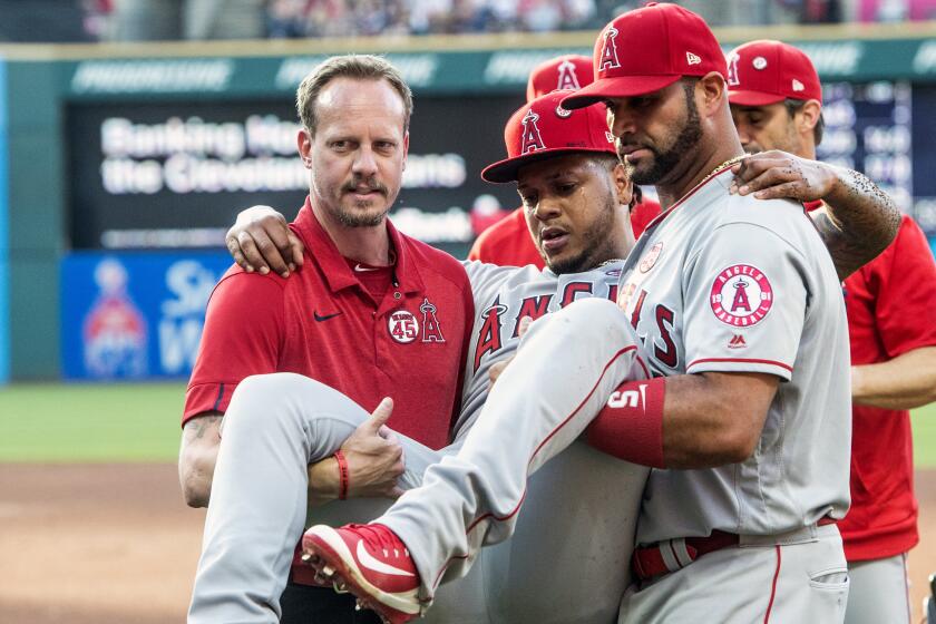 Los Angeles Angels starting pitcher Felix Pena is carried off the field by teammate Albert Pujols and an unidentified trainer during the second inning of a baseball game against the Cleveland Indians in Cleveland, Saturday, Aug. 3, 2019. (AP Photo/Phil Long)