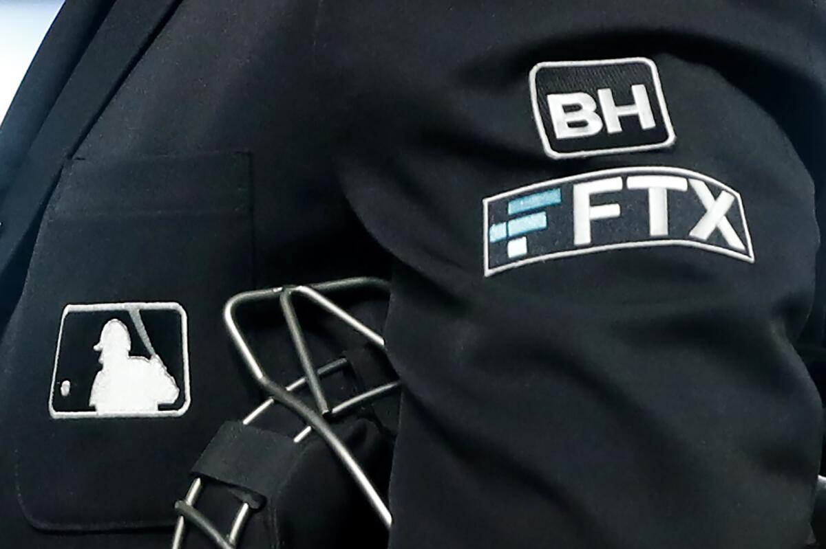 ARCHIVO - Un umpire del plato lleva en su chaque un logotipo del gigante de criptomonedas FTX 