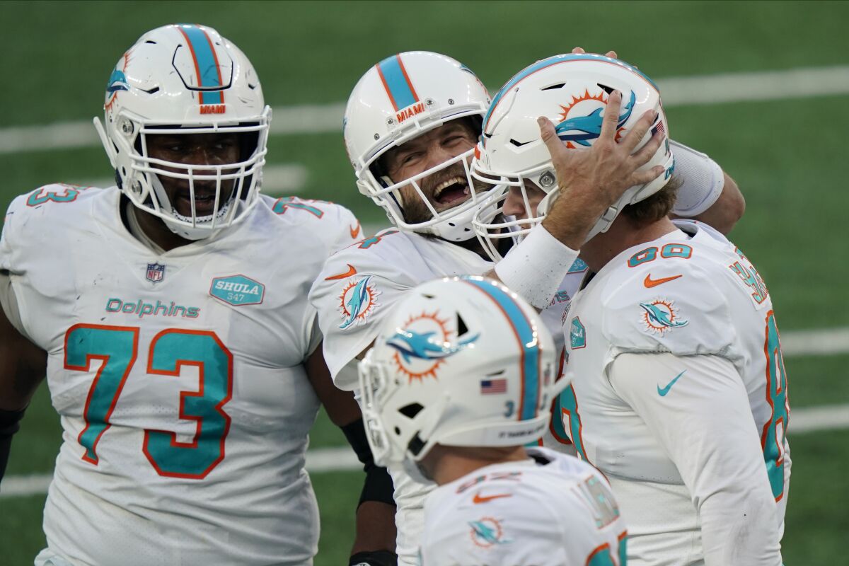 Miami Dolphins quarterback Ryan Fitzpatrick, center, celebrates a touchdown with Adam Shaheen, right, during the second half of an NFL football game against the New York Jets, Sunday, Nov. 29, 2020, in East Rutherford, N.J. (AP Photo/Corey Sipkin)