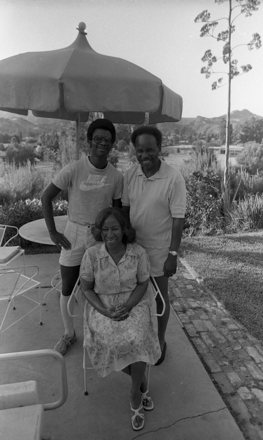 Two men stand behind a sitting woman