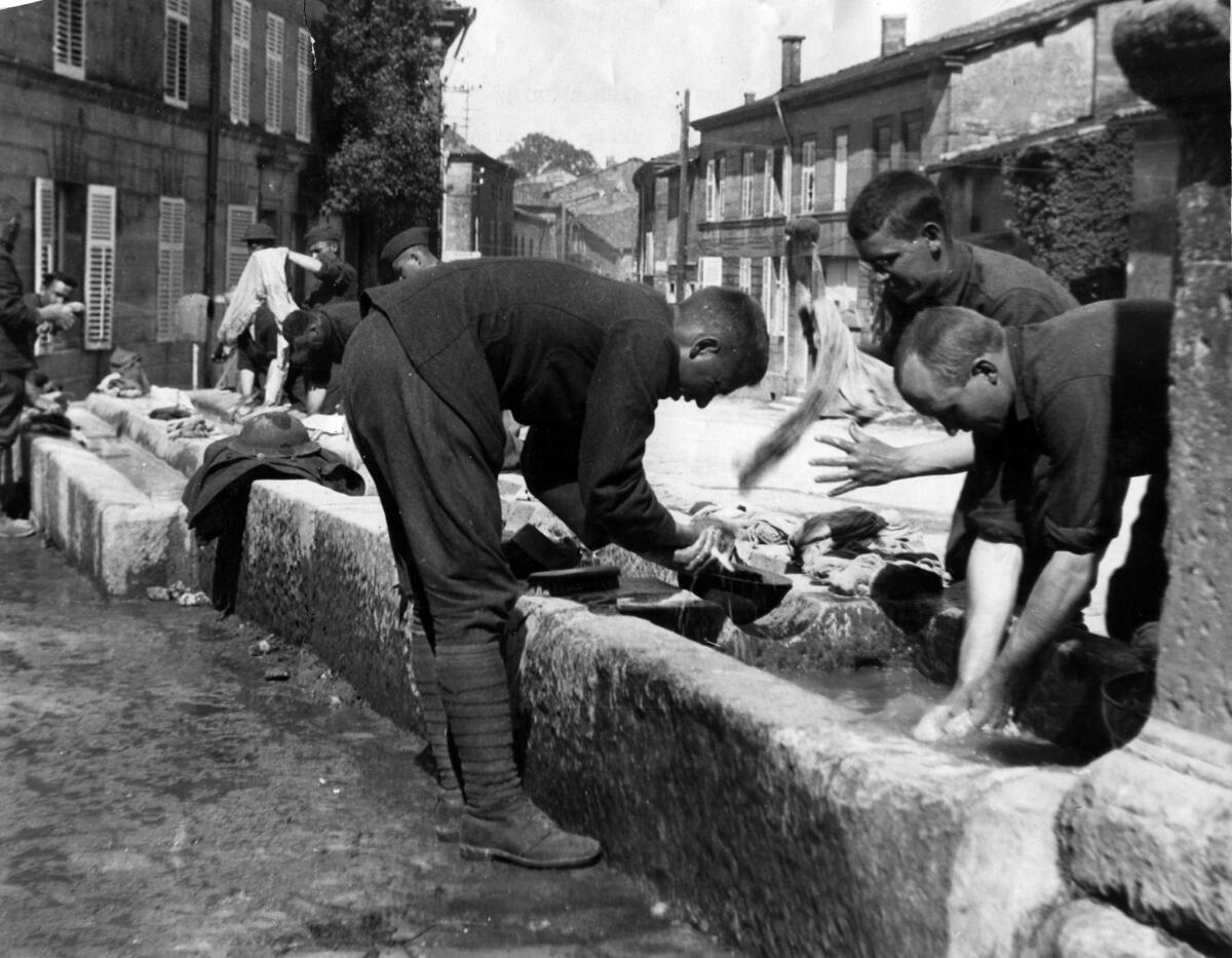 1918: Soldiers take advantage of community washing troughs in village near Bar-le-Duc, France.