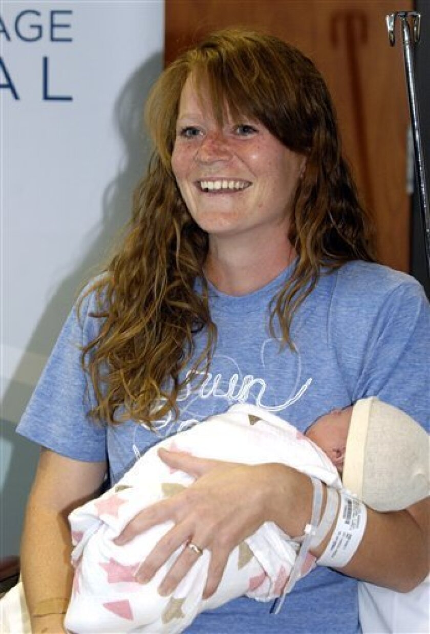 Amber Miller, of Westchester, Ill., holds her baby at Central DuPage Hospital in Winfield, Ill., Monday Oct. 10, 2011. Miller felt contractions a few minutes after finishing the Chicago Marathon on Sunday and gave birth hours later to a baby daughter. (AP Photo/Daily Herald, Mark Black) MANDATORY CREDIT