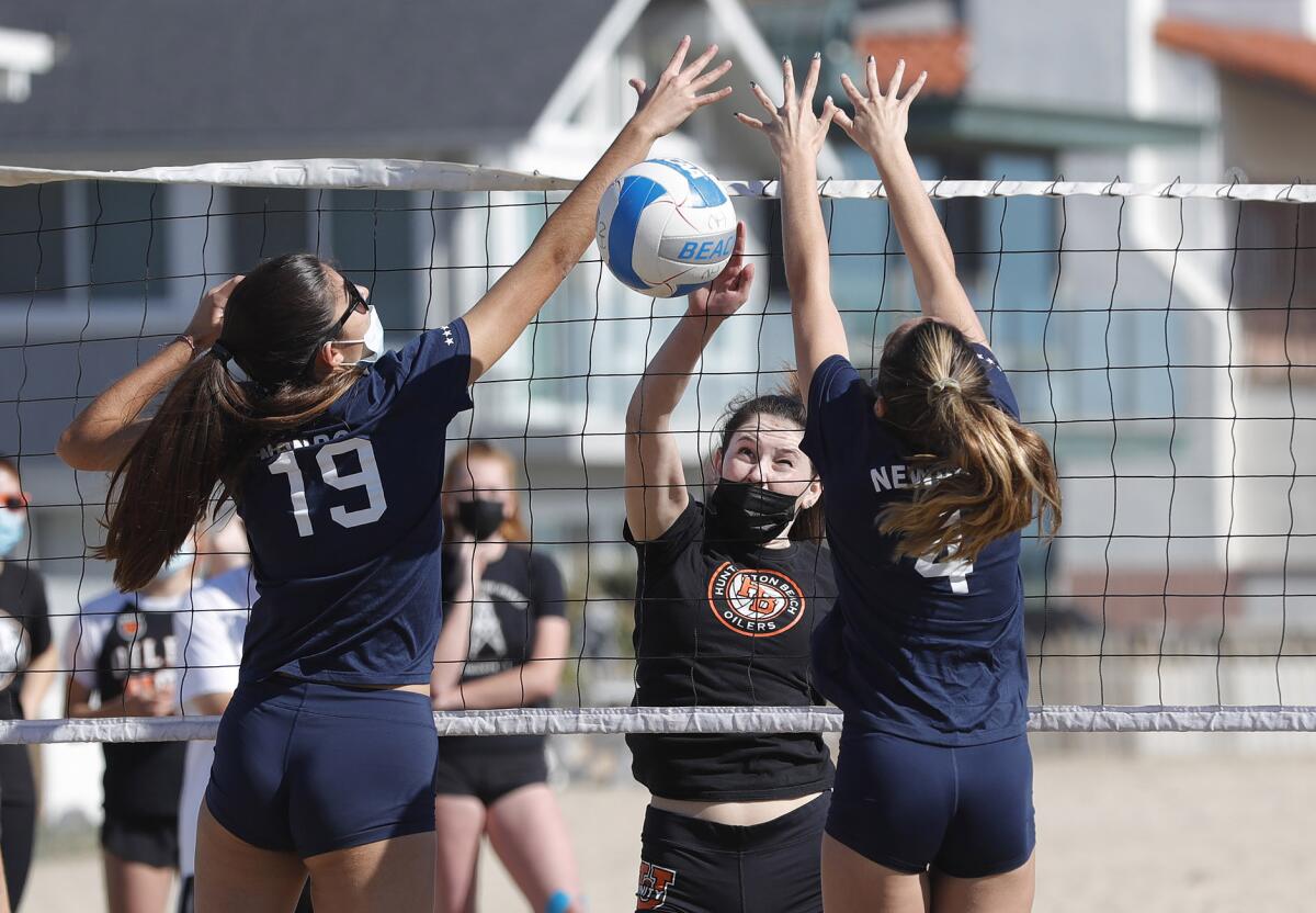 Huntington's Allie Bjork gets a kill past Anabel Kotzakov (19) and Bree Anderson (4) of Newport Harbor.