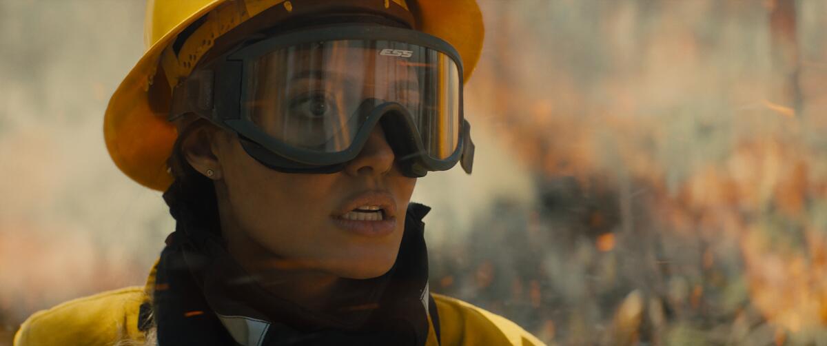 Playing a wildfire-fighter,  Angelina Jolie's character looks alarmed as flames burn in the background 