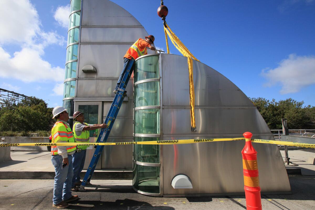 Employees from Ortiz Enterprises prepare to move the top half of a toll booth onto of a truck bed at Catalina View Mainline Toll Plaza along California State Route 73.