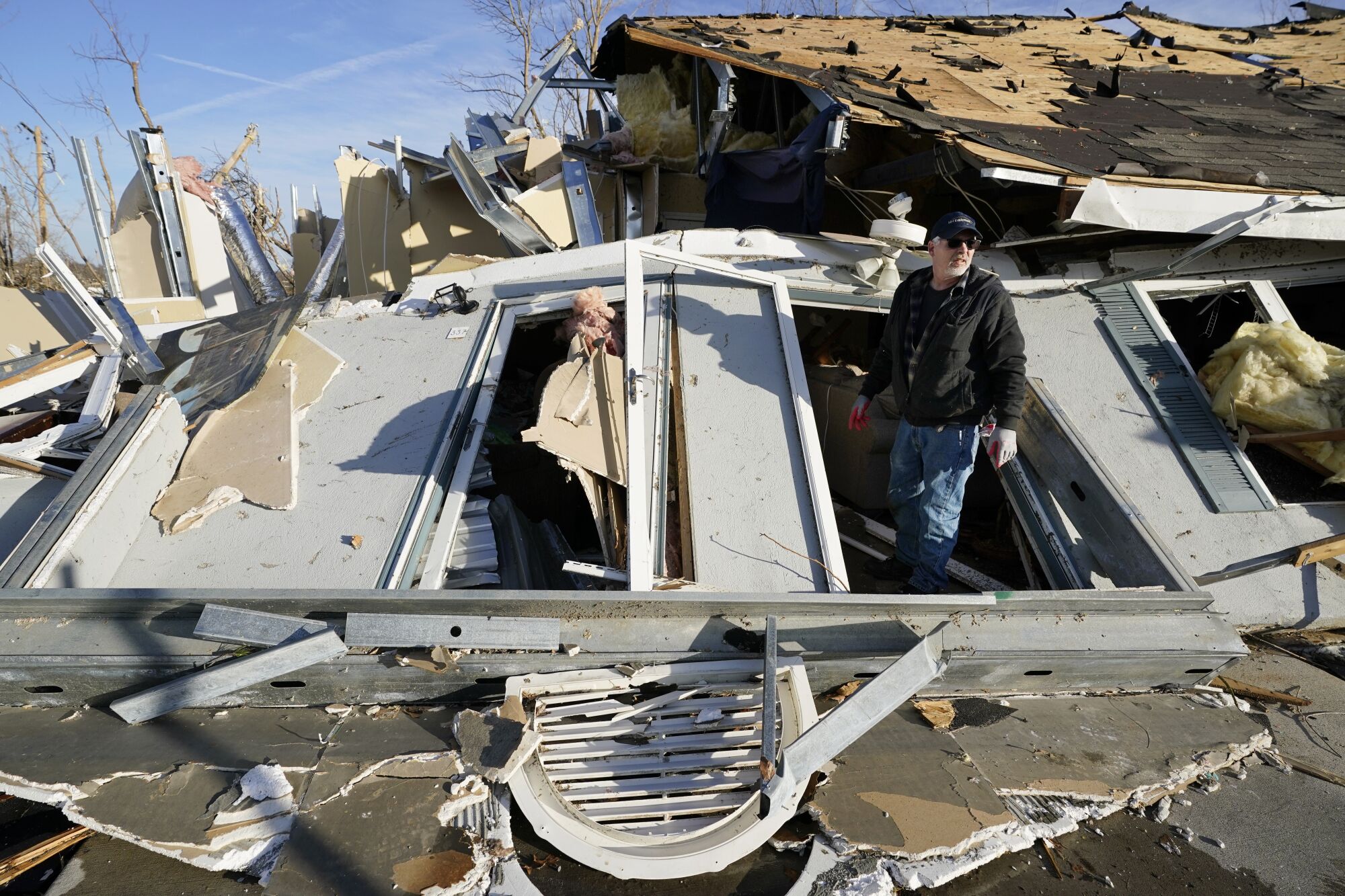 A man exits apartment through a collapsed wall.