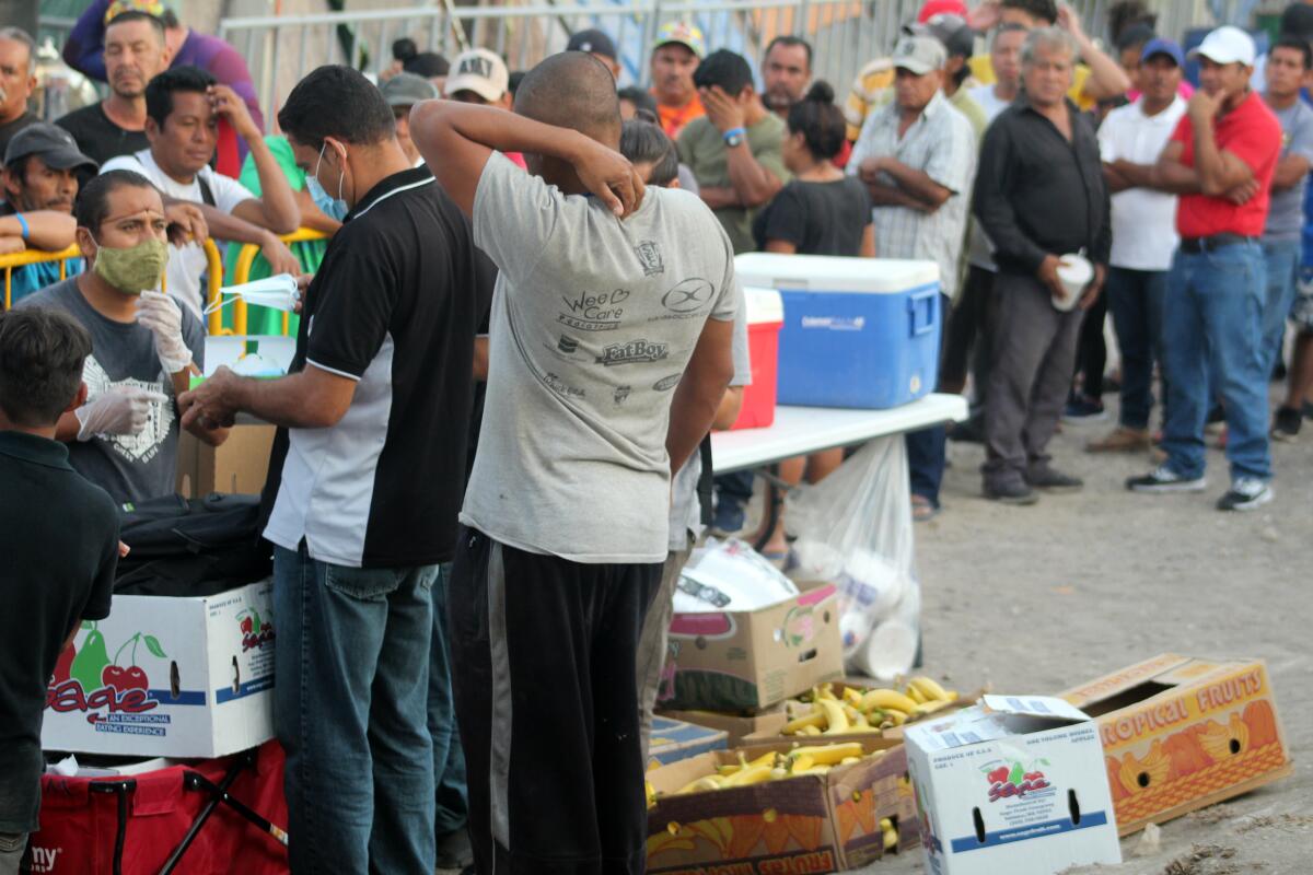 No hay distanciamiento social entre los residentes que hacen fila para cenar en el campamento de Matamoros.