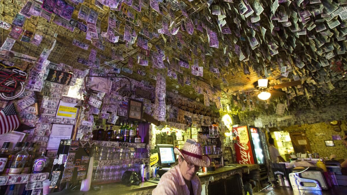 Caryn Waldron tends bar at the Oatman Hotel Restaurant & Saloon, which is covered with dollar bills