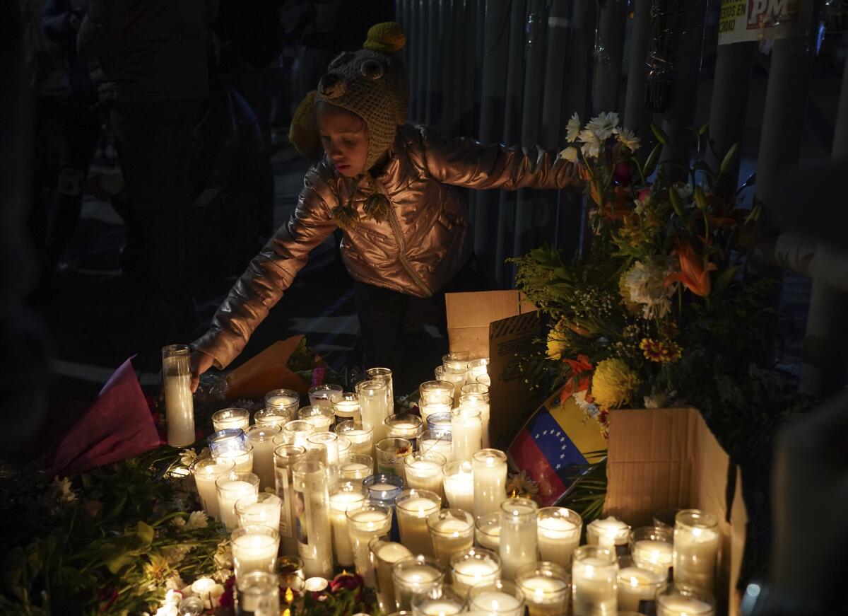 A young girl adds a candle to dozens burning at a vigil for victims of a fire at a migrant detention center.