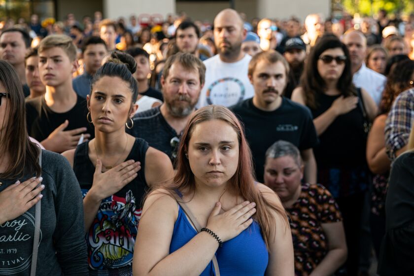 GILROY, CALIF. - JULY 29: Amber Bruce, 23 of Gilroy, center, places her hand over her heart during the singing of the National Anthem, at a candlelight vigil at Gilroy City Hall on Monday, July 29, 2019 in Gilroy, Calif. (Kent Nishimura / Los Angeles Times)