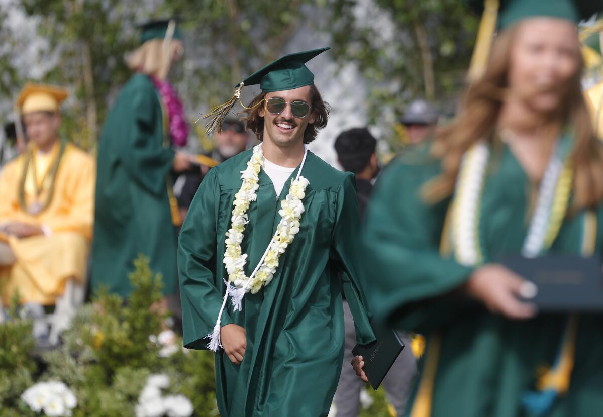 A smiling graduate walks with his diploma during the 2021 Edison High graduation ceremony on Thursday.