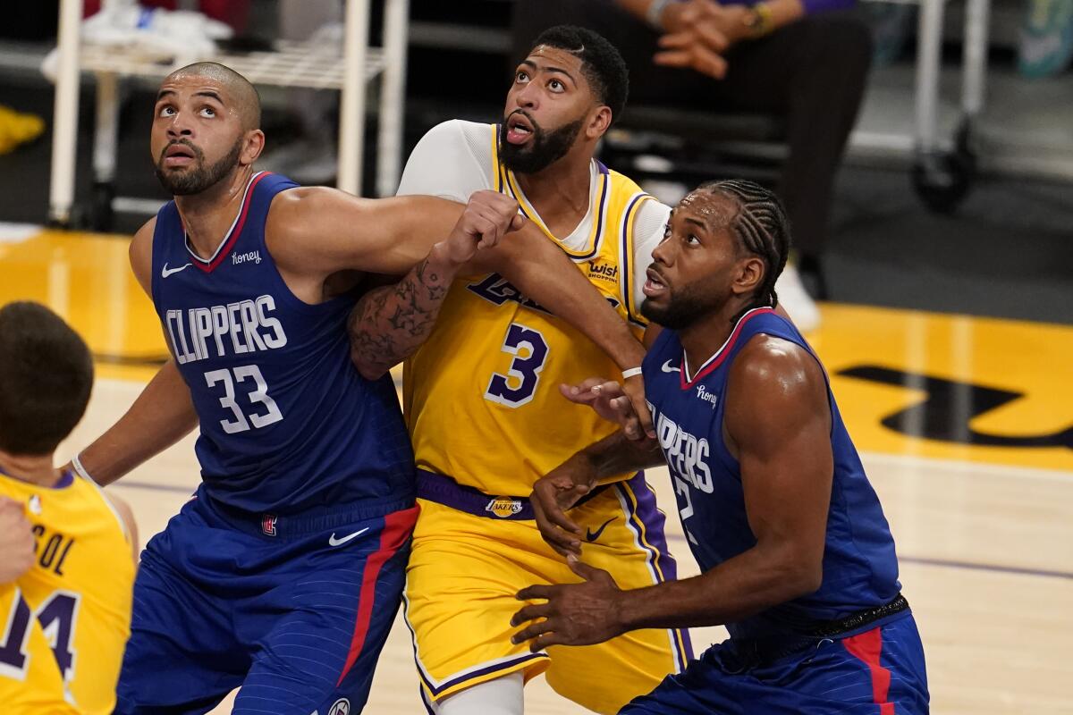 Clippers forwards Nicolas Batum (33) and Kawhi Leonard (2) block out Lakers forward Anthony Davis during the season opener.