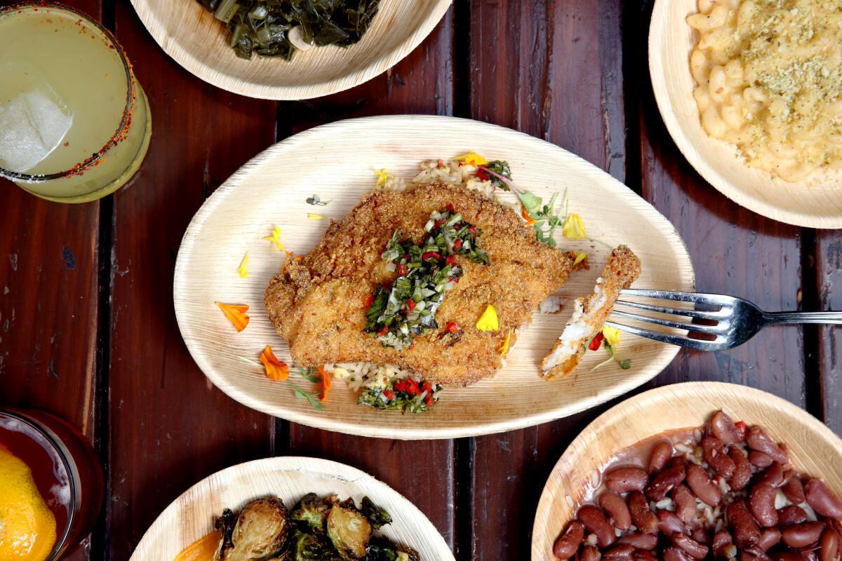 A plate of jerk catfish served with rice, herbed sauce and sides 