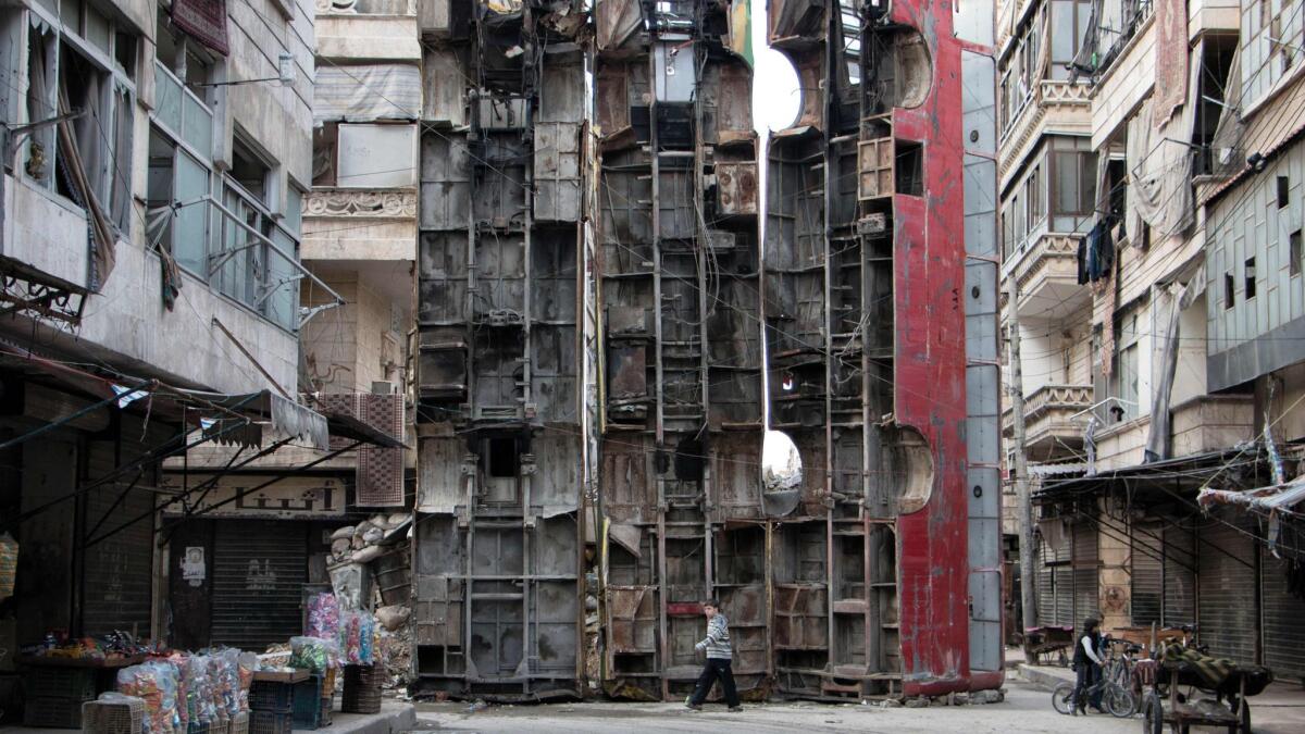 A March 14, 2015, photo shows a young boy walking past a makeshift barricade made of the wreckages of buses to obstruct the view of snipers in the northern Syrian city of Aleppo.