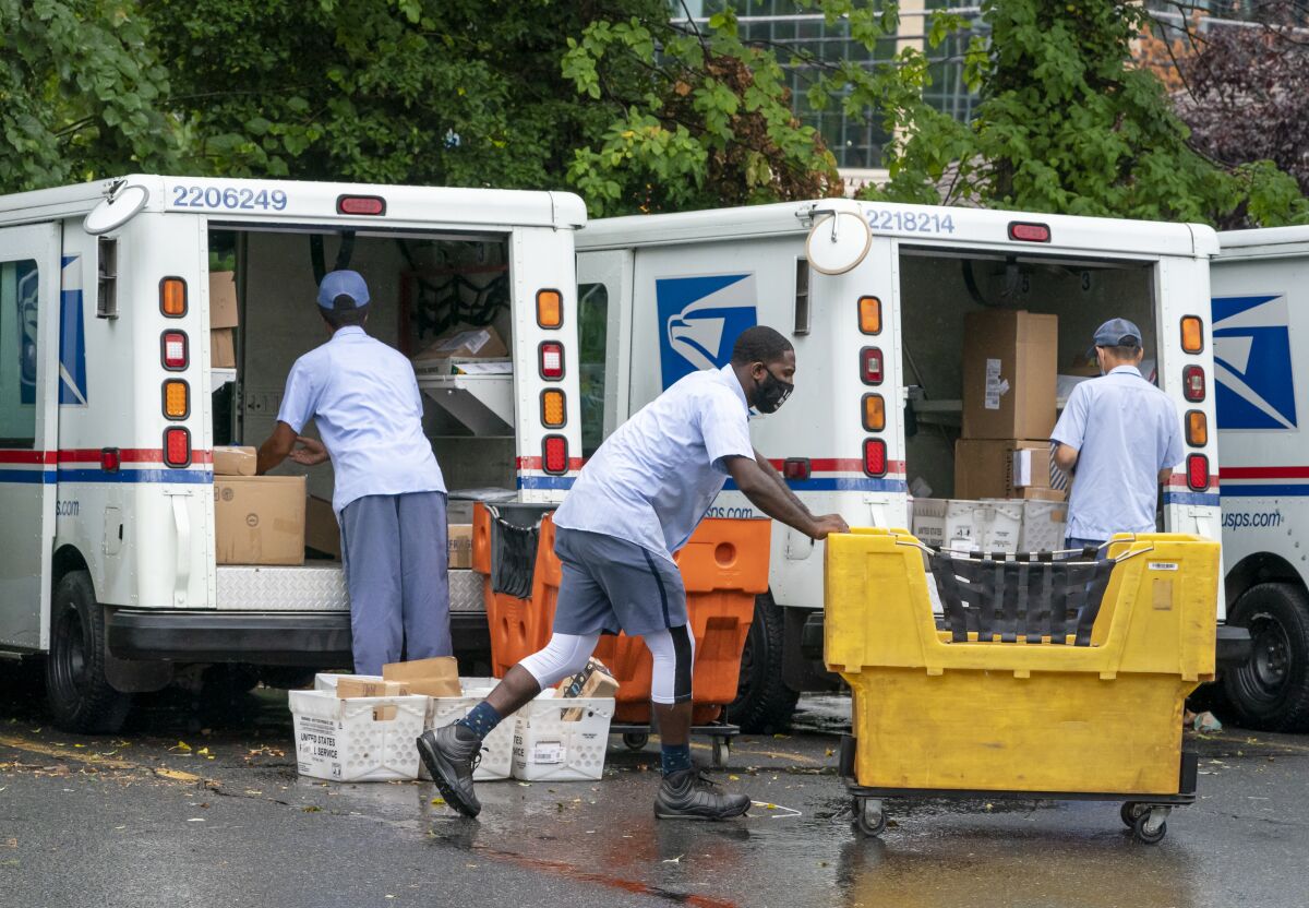 FILE - In this July 31, 2020, file photo, letter carriers load mail trucks for deliveries at a U.S. Postal Service facility in McLean, Va. The success of the 2020 presidential election could come down to a most unlikely government agency: the U.S. Postal Service. (AP Photo/J. Scott Applewhite, File)