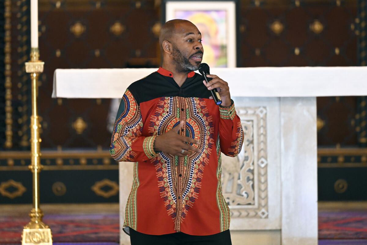 A man stands and speaks into a microphone at Gesu Catholic Church in Detroit.