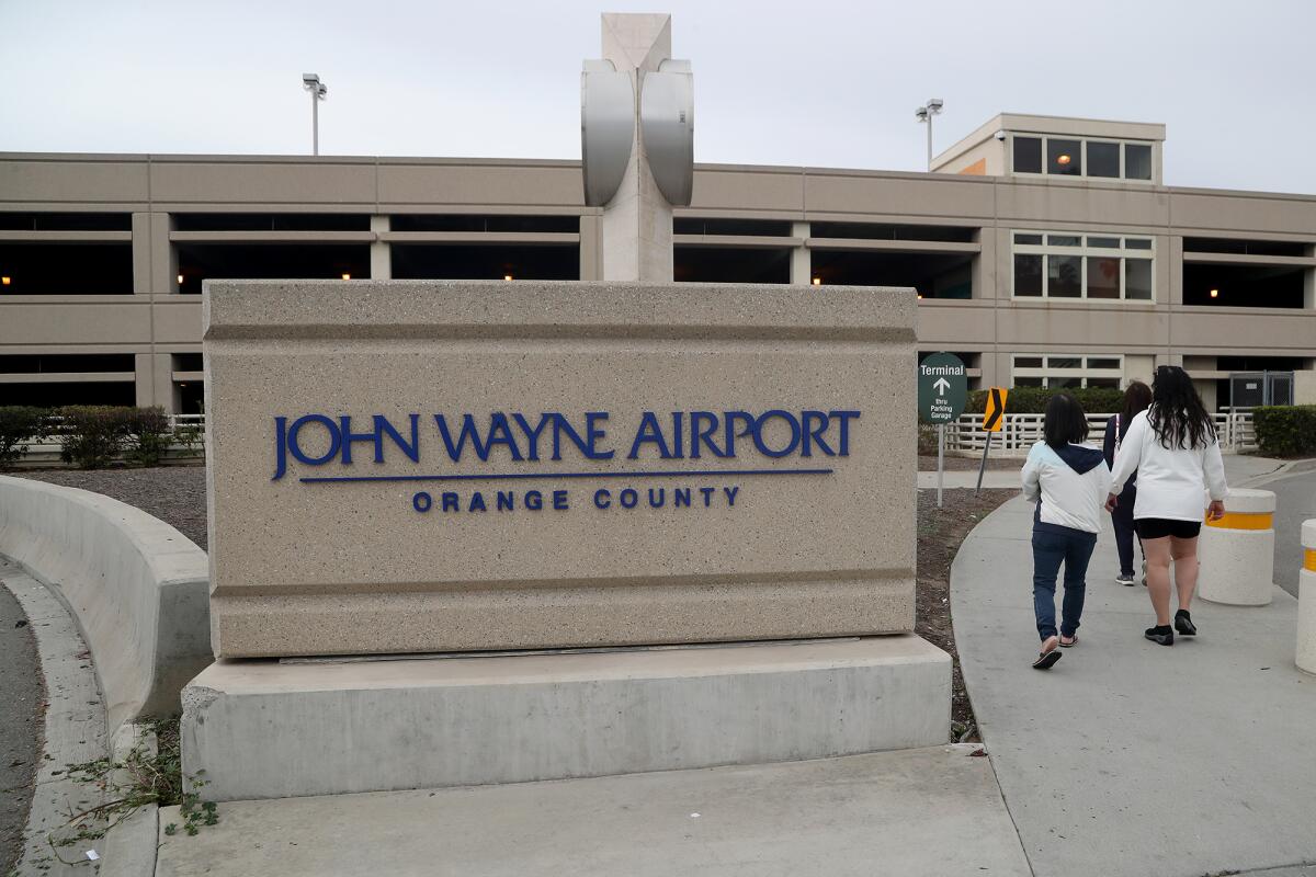 Pedestrians walk into John Wayne Airport on Tuesday in Santa Ana. 