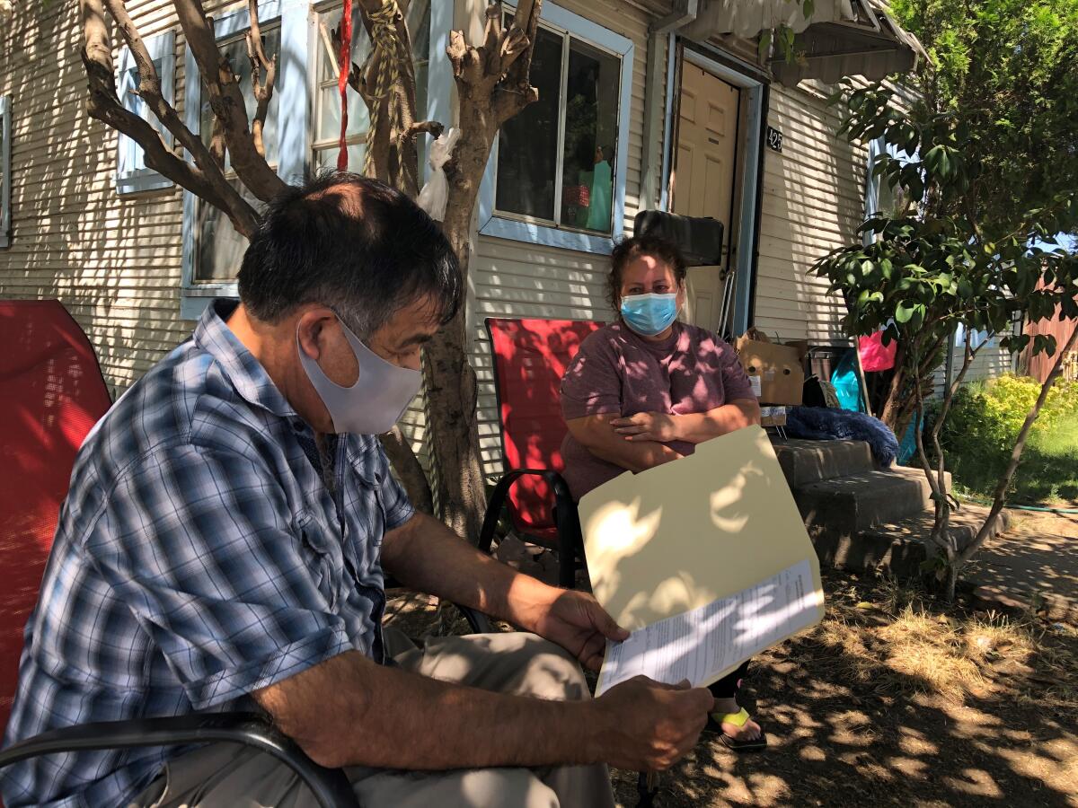 A farmworker advocate reads eviction papers in a manila folder as the woman facing eviction looks on
