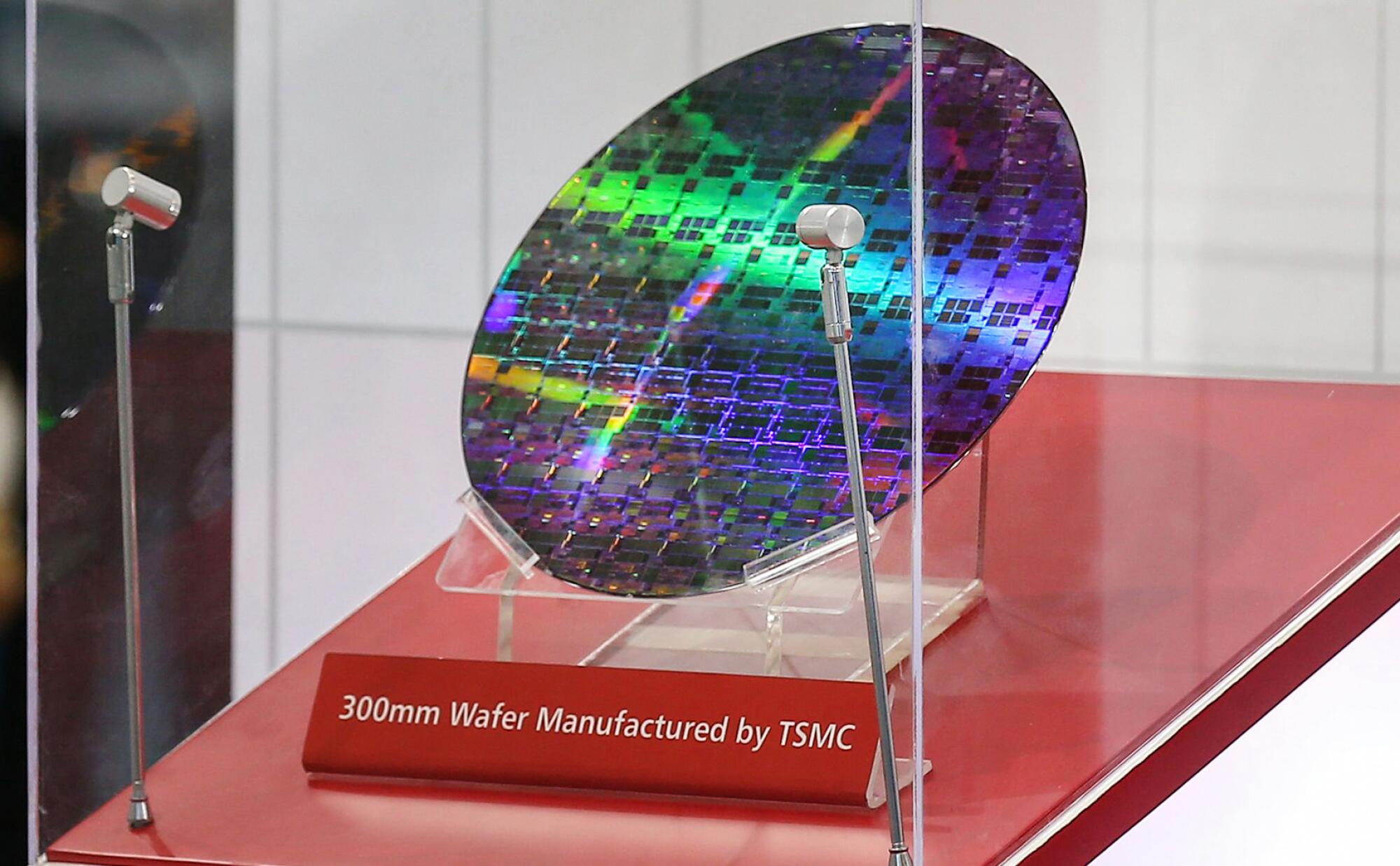 A reflective, circular semiconductor chip on display with a sign that says 300mm Wafer Manufactured by TSMC
