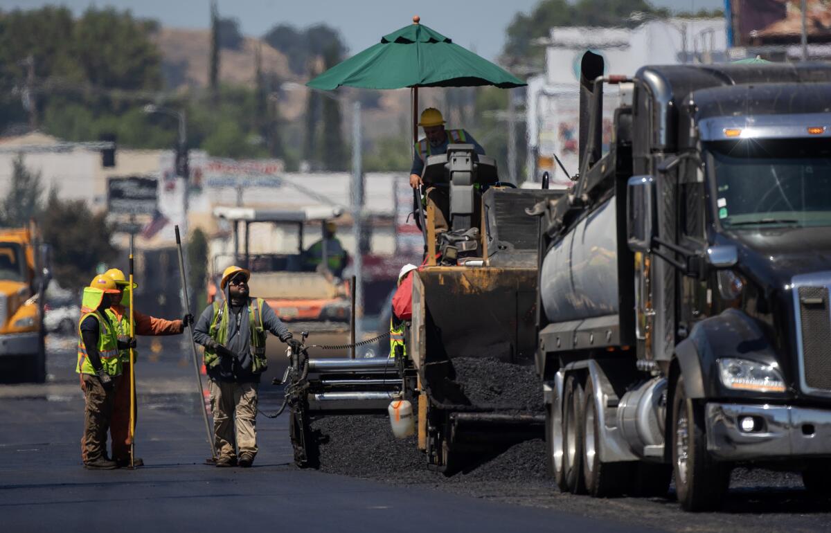 Heat radiates up off fresh asphalt as workers lay down new pavement on Ventura Boulevard in Woodland Hills. 
