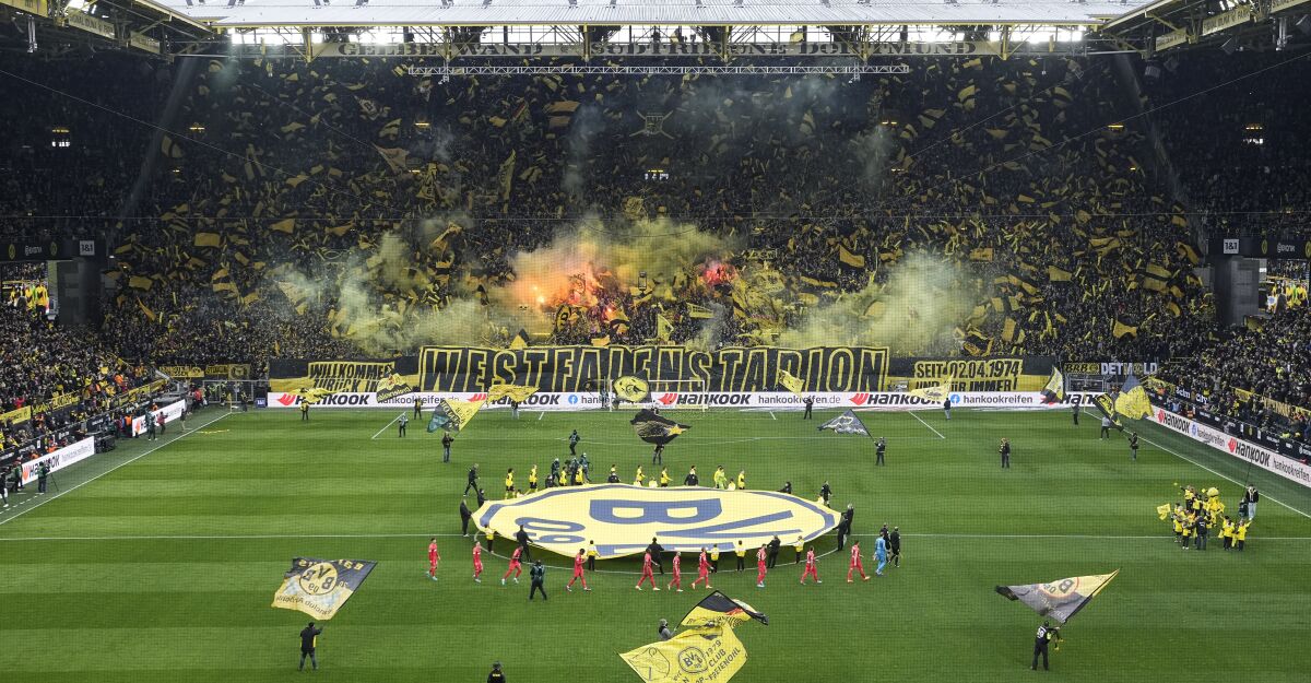 Fans on the famous south tribune celebrate prior the German Bundesliga soccer match between Borussia Dortmund and RB Leipzig in Dortmund, Germany, Saturday, April 2, 2022. After more than two years of coronavirus pandemic, Germany's biggest stadium was sold out with allowed 81,365 spectators. (AP Photo/Martin Meissner)