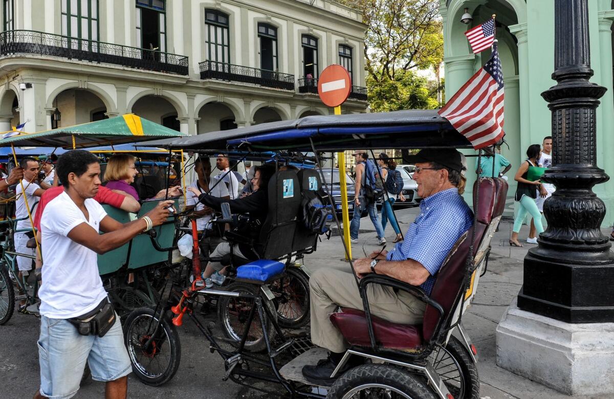 A bicycle taxi with a U.S. flag takes tourists along a street in Havana, Cuba, on Friday, January 30.