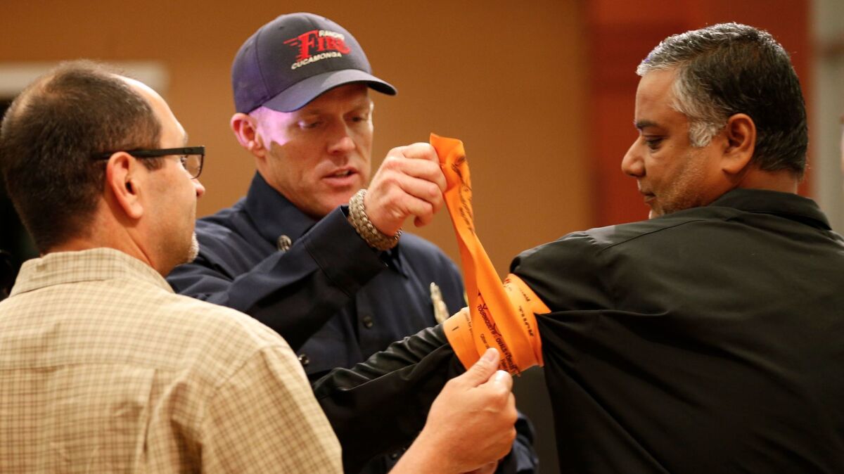 Rancho Cucamonga Fire Capt. Patrick Lewis, center, shows Harlan Medina, left, and Jigish Shah how to wrap a tourniquet.