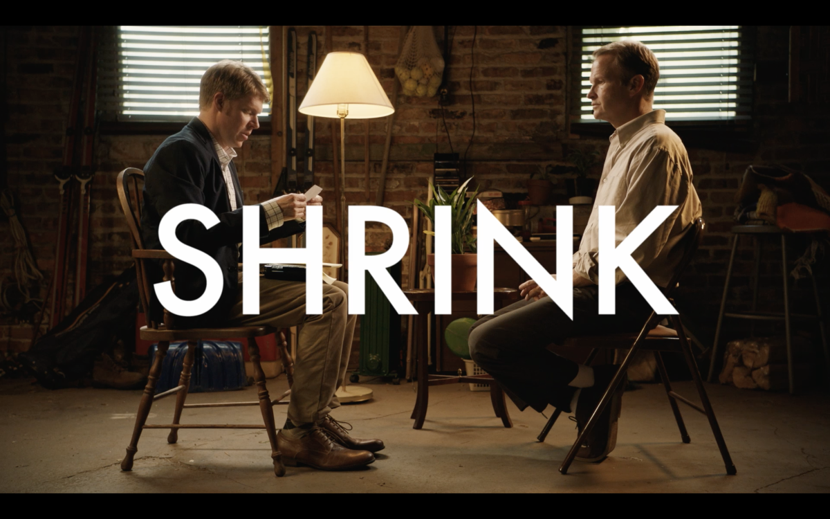 Two men seated facing each other with the word Shrink over it.
