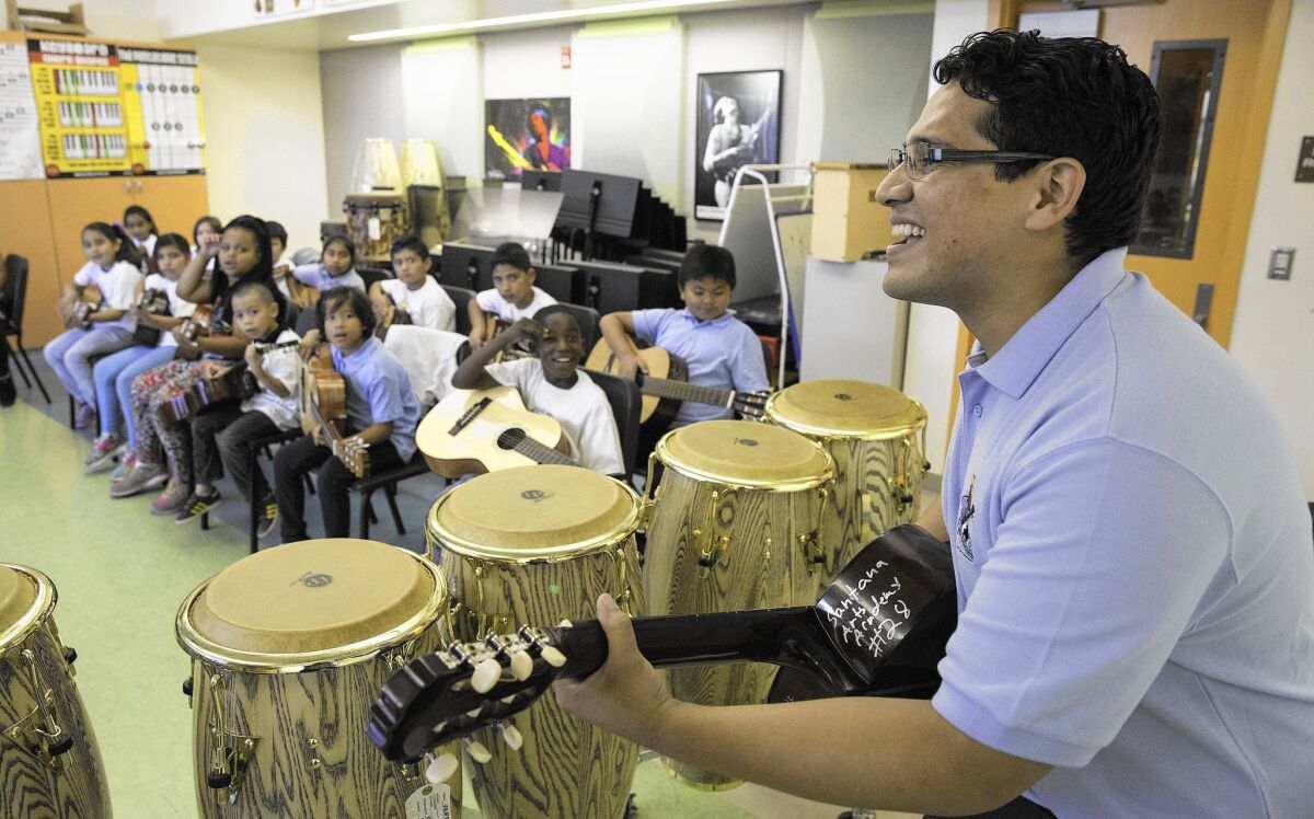 Music teacher Bladimir Castro demonstrates guitar during his class at Carlos Santana Arts Academy in North Hills. The campus is abuzz with visual and performing arts, but the principal has gone outside the school district for help.