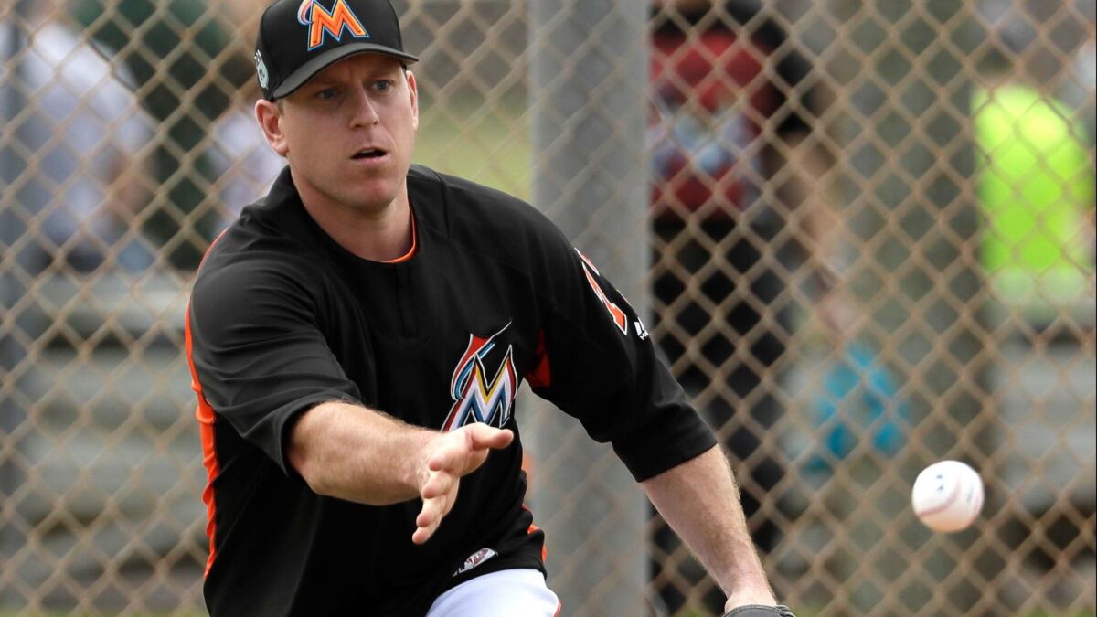 Miami Marlins catcher A.J. Ellis tosses the ball toward home plate during a spring training baseball workout Saturday, Feb. 18, 2017, in Jupiter, Fla.